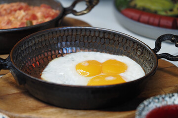 Freshly cooked eggs in a rustic pan at breakfast