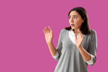 Beautiful young afraid woman on purple background