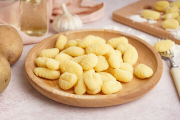 Wooden plate with tasty gnocchi and fork on light background, closeup