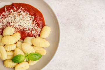 Plate of tasty gnocchi with tomato sauce and cheese on white background
