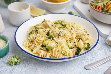 Delicious fusilli pasta with broccoli and cheese in bowl on light background, closeup
