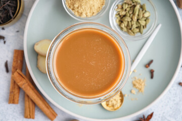 Glass of tasty masala tea with different spices on light background, closeup