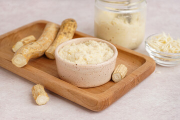 Horseradish sauce in bowls and jar with ground horseradish on white background