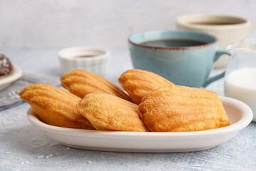 Plate with delicious madeleines on white grunge background
