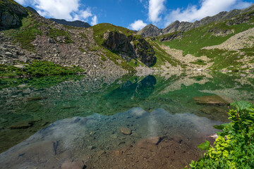 View of the Dukka lake "Rybka" on the Malaya Dukka River on the slopes of the Arkasar ridge in the North Caucasus on a sunny summer day, Arkhyz, Karachay-Cherkessia, Russia © Ula Ulachka