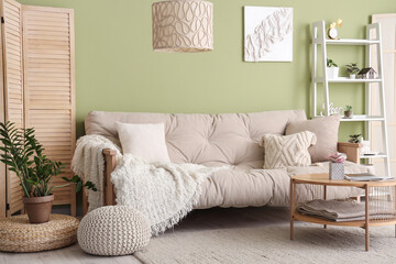 Stylish interior of green living room with soft sofa, coffee table and shelving unit