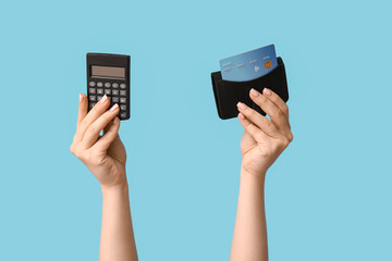 Female hands with credit card and calculator on blue background