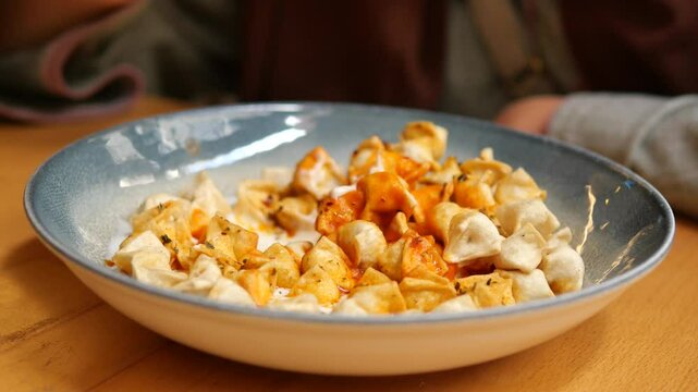 Woman eating manti sitting on a table 