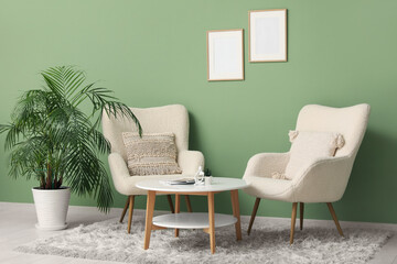 Armchairs and coffee table near green wall in room