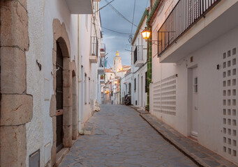 Fototapeta premium Early morning view of a quiet, narrow street in Cadaques, leading up to the Church of Santa Maria