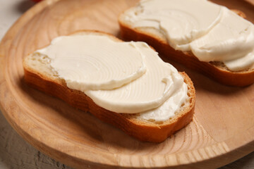 Wooden plate of tasty bruschetta with processed cheese on grey background. Closeup