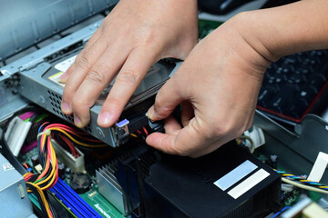 A computer technician is plugging in the power and data cables to the hard disk.