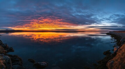 Fototapeta premium A peaceful sunrise over the Westfjords road, reflecting on the calm waters of the fjords.