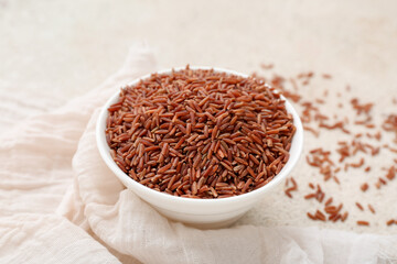 Bowl with raw brown rice on light background