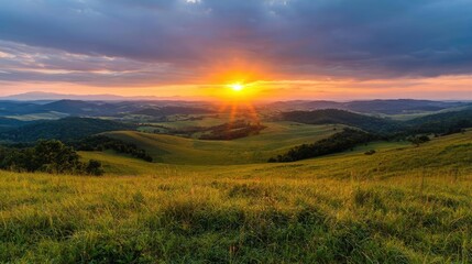 Obraz premium Sunset over rolling hills and green meadows