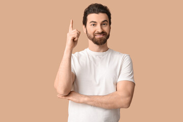 Young man pointing up on beige background