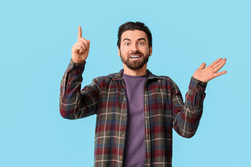 Young man pointing up on blue background