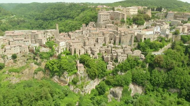 Aerial summer afternoon view of Sorano. Rooftops of an ancient medieval hill town hanging from a tuff stone over the Lente River. Etruscan heritage. Province Grosseto, Tuscany, Italy.