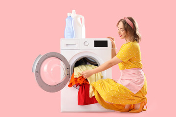 Young pin-up housewife doing laundry on pink background