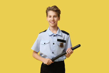 Teenage police officer with baton on yellow background