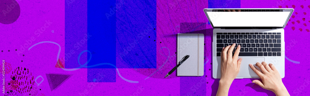Poster person using a laptop computer with a notebook - flat lay