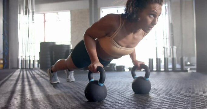 Doing push-ups using kettlebells, woman exercising in gym for fitness