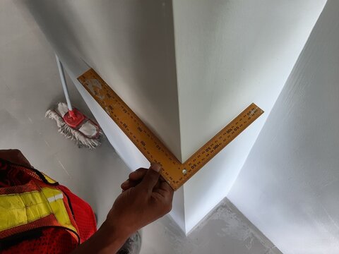 Accurate corner measurement with a yellow ruler for quality control in interior wall alignment