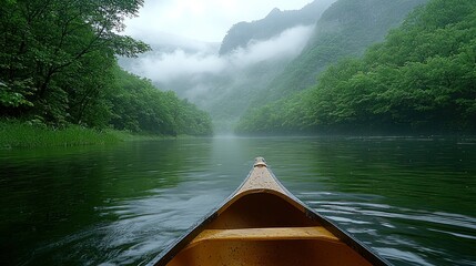 Fototapeta premium Misty River Journey: Canoeing Through Serene Mountains