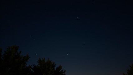 Fototapeta premium A serene autumn night sky with faint stars shining brightly against the clear, dark backdrop.