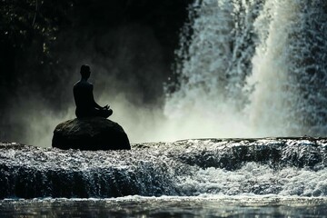 Obraz premium Serene Meditation by a Waterfall: A Peaceful Moment of Reflection in Nature's Tranquility