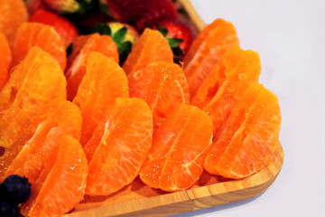 Peeled sweet oranges on a beautifully arranged wooden tray and white background.