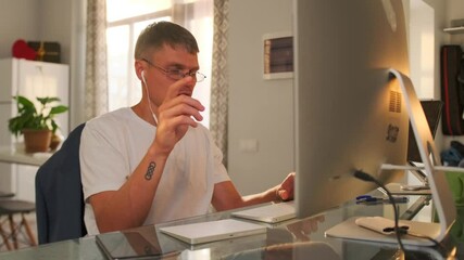 After finishing the video conference on his computer with a positive attitude, the remote worker waves goodbye, leans back in his chair, and exhales with satisfaction and relaxation.