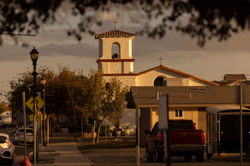 Setting sun shines on a historic church and buildings of downtown Firebaugh, California, USA.