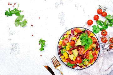 Mexican vegan corn salad with red beans, avocado, tomatoes, onion and cilantro. White background, top view
