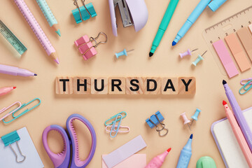 Word Thursday made of wooden blocks with colorful pastel stationery on a beige background