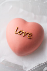Heart-shaped dessert covered with pink chocolate with Love Inscription. Valentine day sweets.