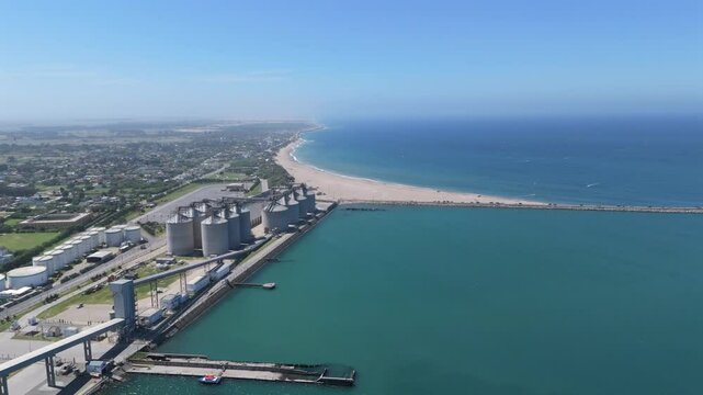Port of necochea silos, beach, and ocean under a clear blue sky, aerial view