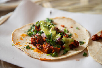 Delicious Mexican tacos with handmade tortillas with red pork chorizo and spicy green sauce.