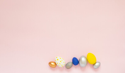 Colored decorated eggs on pastel pink background. Space for text. Happy Easter 