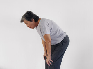 Unhappy Asian elder woman got knee pain symptom, moaning, hand resting on both knees, standing...