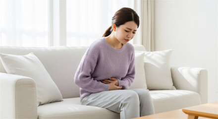 腹痛で顔を歪める女性