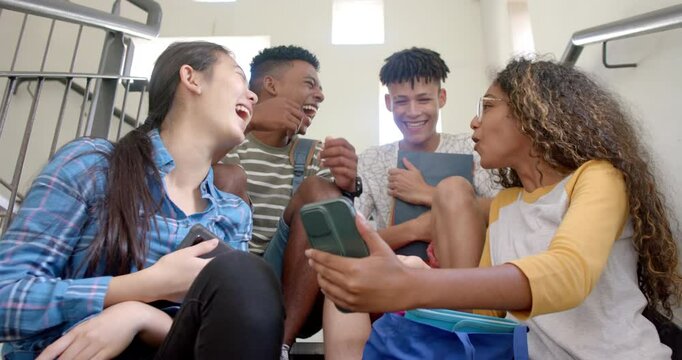 Diverse teenagers share a laugh on high school stairs