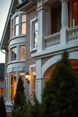 Luxury Home Exterior at Dusk: Modern Architecture and Classic Design. Real Estate Photography showcasing elegant facade, balcony, and warm lighting.