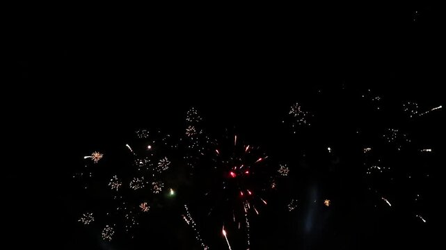 Brilliant burst of colorful fireworks illuminating the night sky, radiating golden and silver streaks with sparkling lights, creating a celebratory and festive atmosphere against the dark night sky