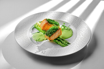 A beautifully plated salmon fillet, seared to perfection and served with tender asparagus spears. The dish is garnished with fresh herbs and a drizzle of citrus sauce