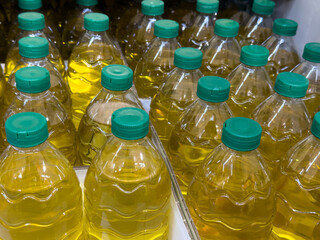 Yellow vegetable oil filled in an artificial pat bottle. In the store, oil bottles are stacked in paper boxes.