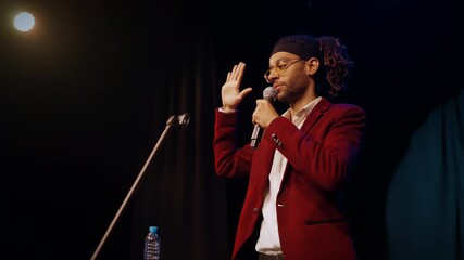 Portrait of charismatic host of comedy show, african man with microphone. Contemporary entertainment in nightclubs, trendy stand-up comedy performance, handsome male speaker performing on stage