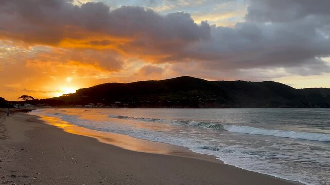 Mediterranean Sea waves rolling on the sandy shore of Lacona village on Elba island, Italy at sunset