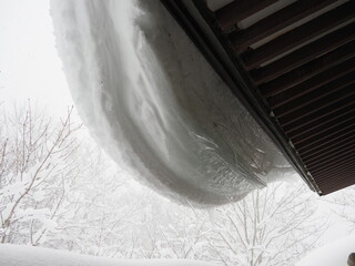 屋根にぶら下がる雪
