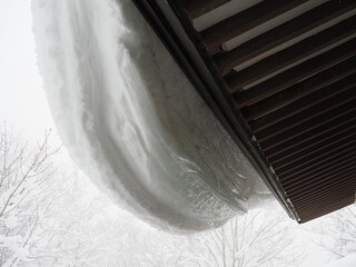 屋根にぶら下がる雪
